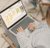 Young woman sitting on a garden chair on the balcony with a laptop on her legs showing a whiteboard for agile management.