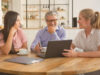3 people sitting at a table with a laptop in front of them