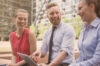 3 people from consultant community of conceptboard laughing outside and having a laptop in the hands