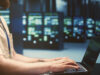 Dedicated server and a person working in a server room on a laptop