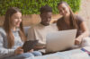 3 students looking in a laptop and using conceptboard for their studies
