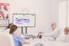Pharma and healthcare. 4 people from the medical industry sitting at a meeting table looking at a screen with a board opened. They use a secure collaboration tool
