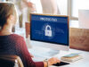 A person in front of has a computer with a security shield on it.