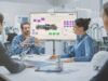 4 people in a meeting room with a big screen on the background with conceptboard open on it. Working in defence industry using online collaboration tool