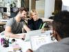 three people brainstorming together. There is Conceptboard board open on the laptop with task management tool